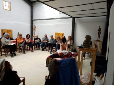 Encuentro de dibujo al natural Grupo de personas sentadas en sillas, participando en una actividad en un espacio compartido.