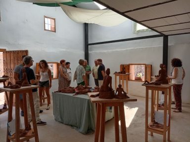 Exposición del curso de modelado Grupos de personas observando esculturas en un espacio artístico luminoso.