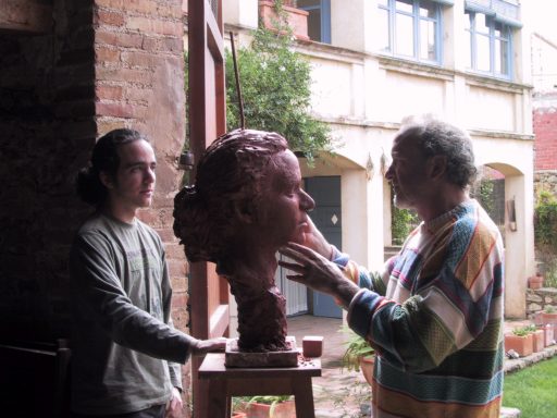 Un hombre modelando con arcilla el retrato de un joven que posa frente a él