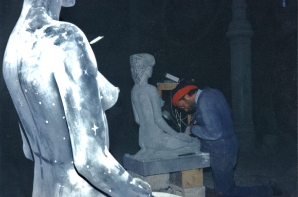 El escultor convirtiendo la piedra en una figura de una mujer sentada sobre sus talones