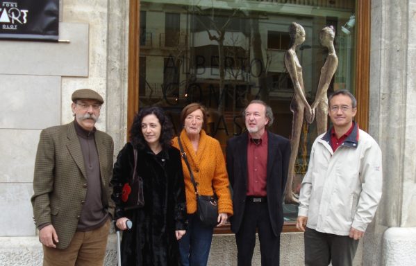 Tres hombres y dos mujeres posando para la foto frente a un escaparate en el que se ve una escultura de dos mujeres cogidas de las manos