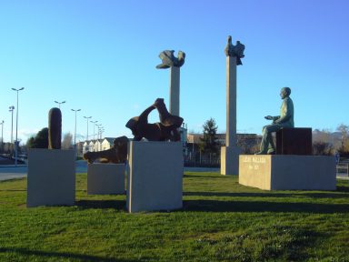 Esculturas instaladas sobre peanas de diferentes tamaños en un espacio verde al aire libre bajo un cielo despejado.