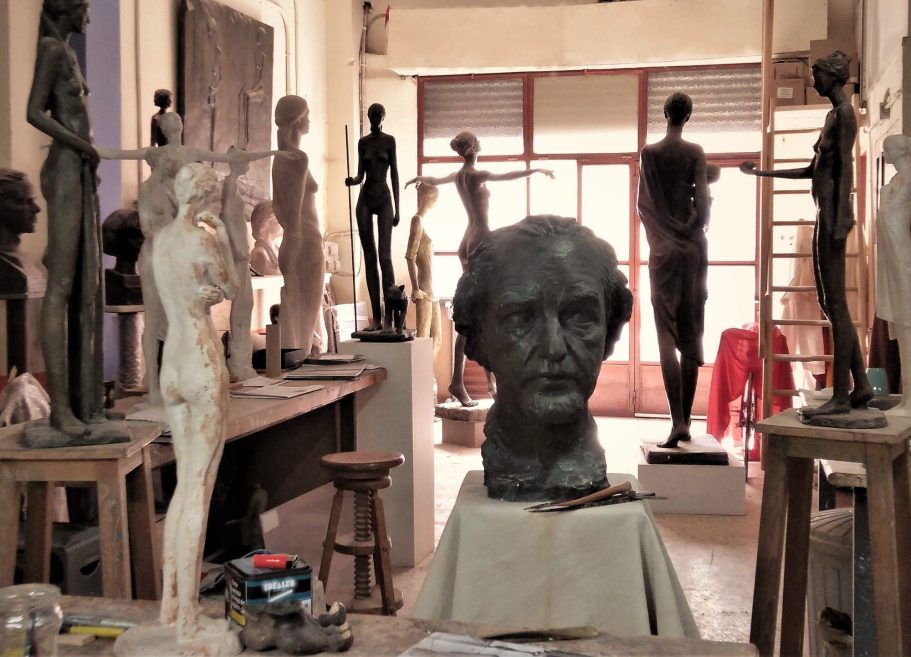 Taller de escultura con varias estatuas y bustos en un ambiente artístico.