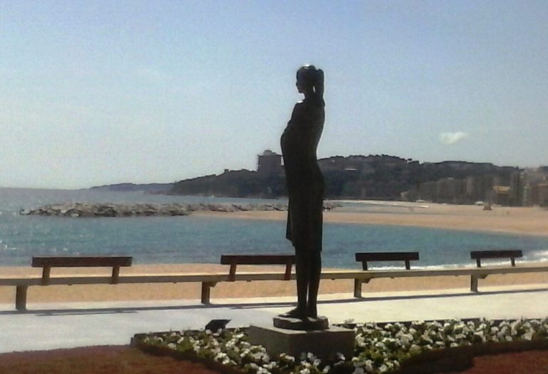 Estatua de una mujer de pie junto a una playa