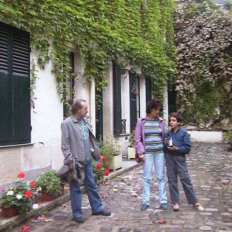 El autor, con su mujer e hijo frente a una casa en una calle con vegetación 