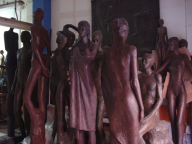 Grupo de esculturas de figuras humanas, talladas en tono oscuro, en un entorno artístico.