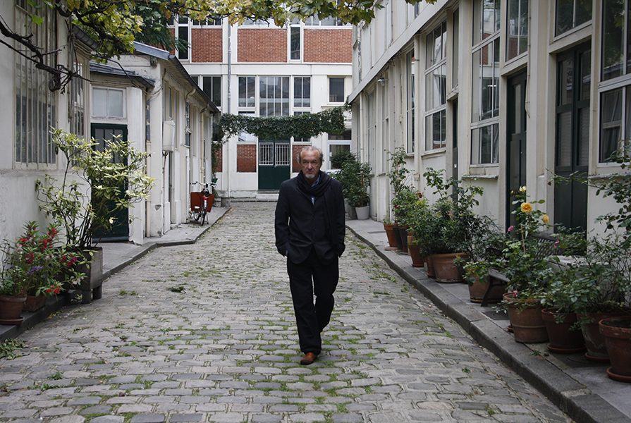 Alberto Gómez Ascaso caminando por una calle de París llena de macetas con plantas frente a las casas