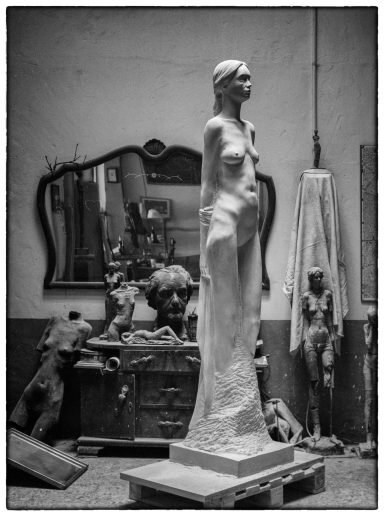 Escultura en blanco y negro de una escultura de piedra que representa una mujer en un taller.