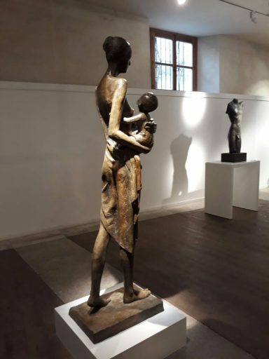 Escultura de una madre sosteniendo a su hijo en un entorno de museo.