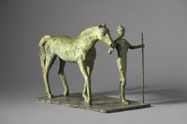 Escultura de una mujer sujetando una vara con una mano acompañada por un caballo, ambos en tonos verdes, sobre una base rectangular.