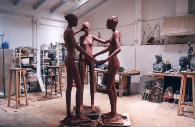 Tres esculturas de hormigón en un estudio artístico, representando figuras humanas.