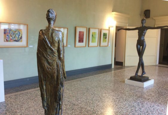 Esculturas de bronce en una galería con obras enmarcadas en las paredes.