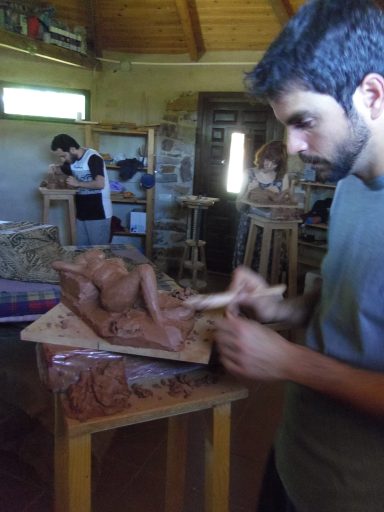 Joven escultor modelando una figura en arcilla en un taller de arte.