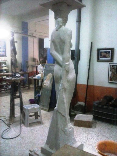 Escultura de una figura humana de pie, de espaldas, en un taller de arte.