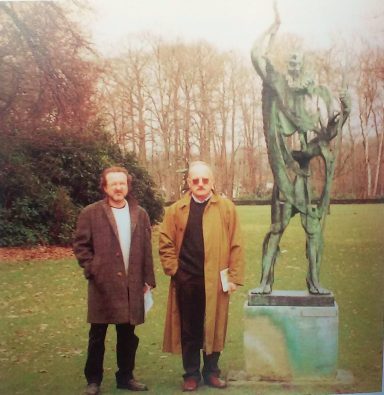 Dos hombres en un parque junto a una escultura 