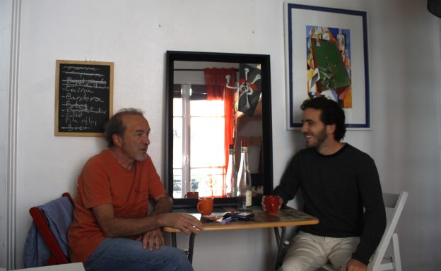 Dos hombres conversando sentados en un cuarto 